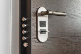 Un serrurier vérifie une serrure de porte d'entrée avant une vente immobilière